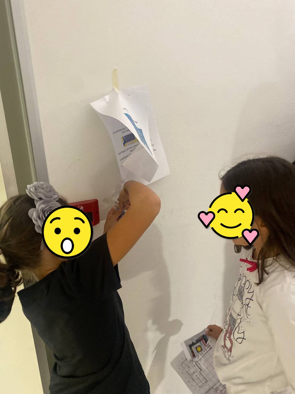 Photo of two girls intent on taking an electronic component from an envelope and reading the question